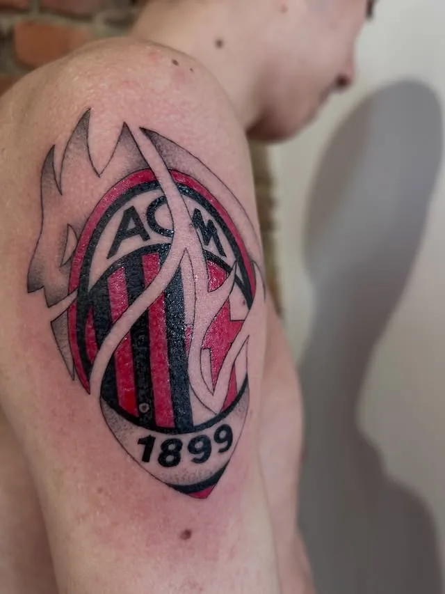 Tatuaggio illustrativo del logo AC Milan sulla spalla realizzato da Anny