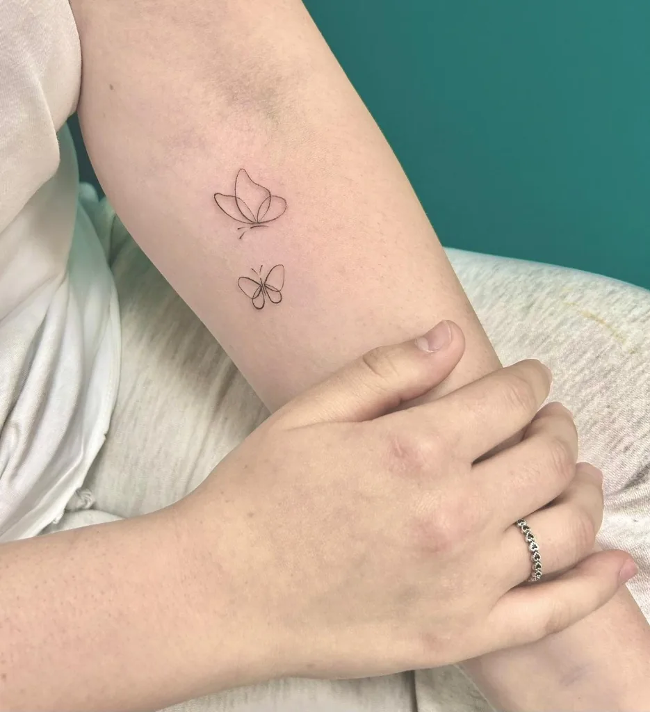 Tatuaggio di due farfalle stilizzate fine line sul braccio