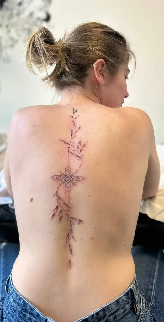 Tatuaggio ramo botanico floreale fine line lungo la colonna vertebrale con mandala geometrico