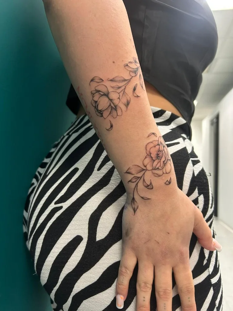Tatuaggio floreale fine line con due rose sfumate sull'avambraccio e sul polso realizzato da Anny