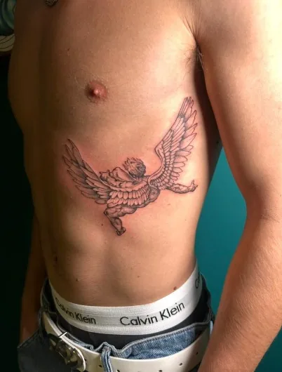 Tatuaggio illustrativo in bianco e nero di un putto angelo volante sul costato realizzato da Anny