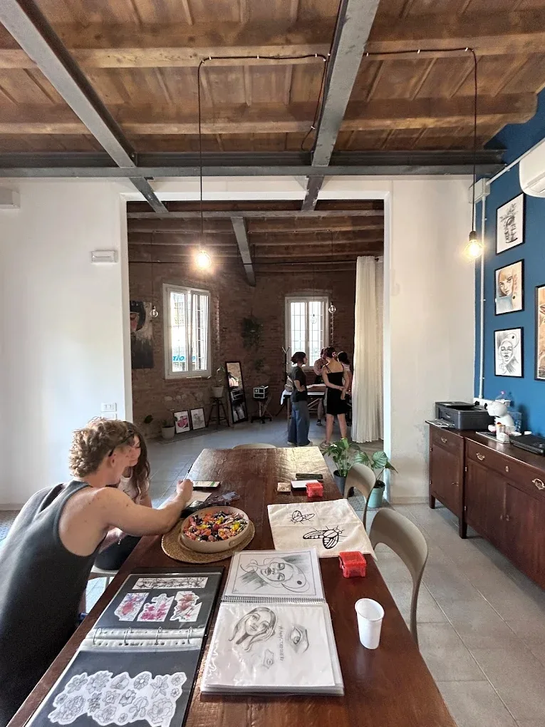 Tavolo da disegno in legno all'interno dello studio Stain Lab con schizzi e opere d'arte esposte