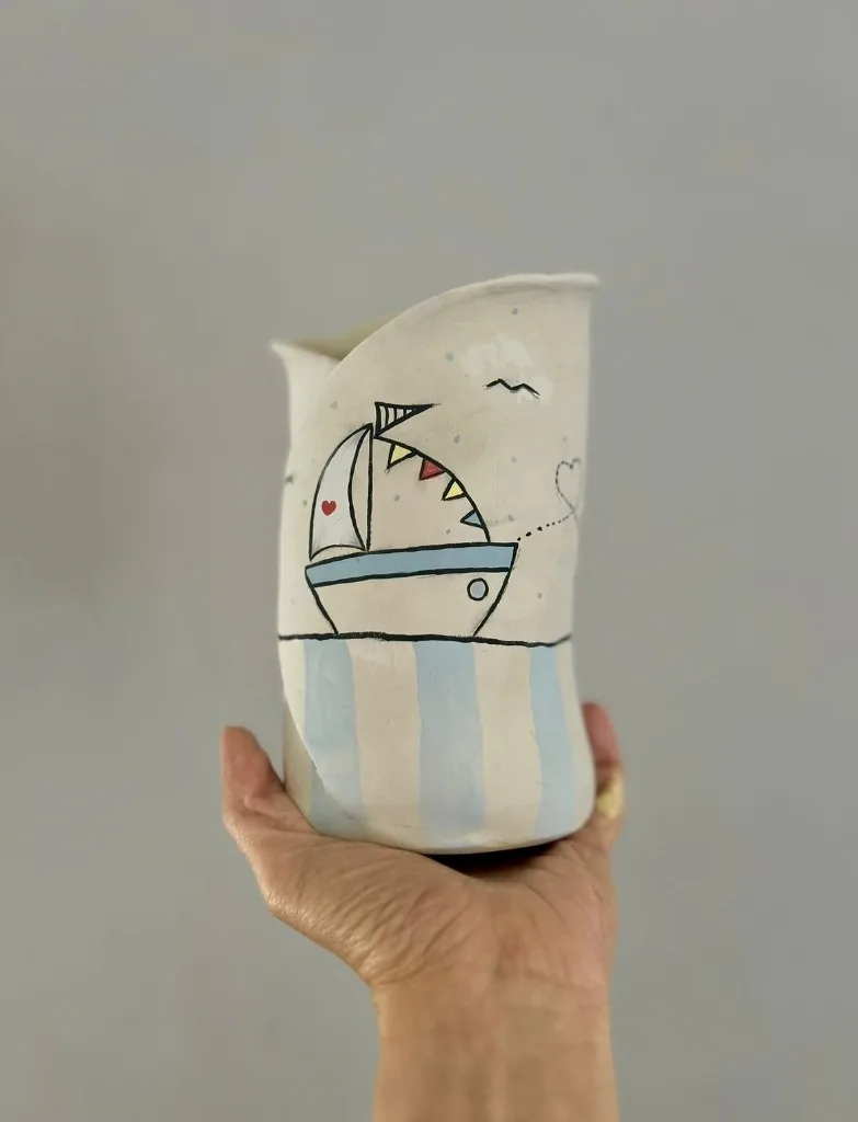 Tazza svasata in ceramica con barca a vela dipinta su righe verticali azzurre